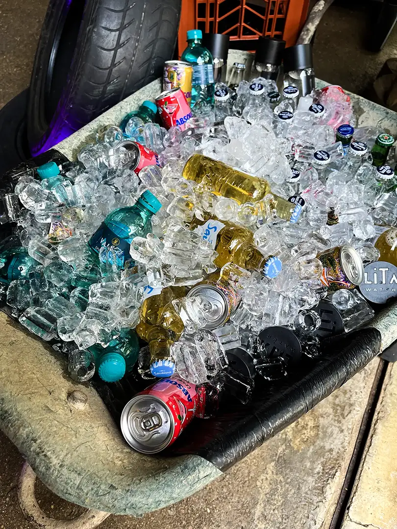 Wheelbarrow filled with ice and various bottled and canned drinks including water and beer.
